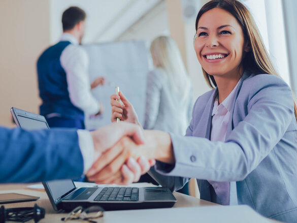 laughing women in business outfit shaking hands