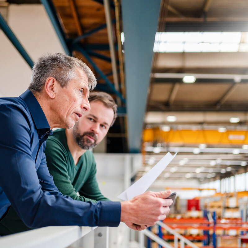 Zwei Männer stehen in einer Halle und diskutieren über Pläne für energieeffiziente Kühllösungen